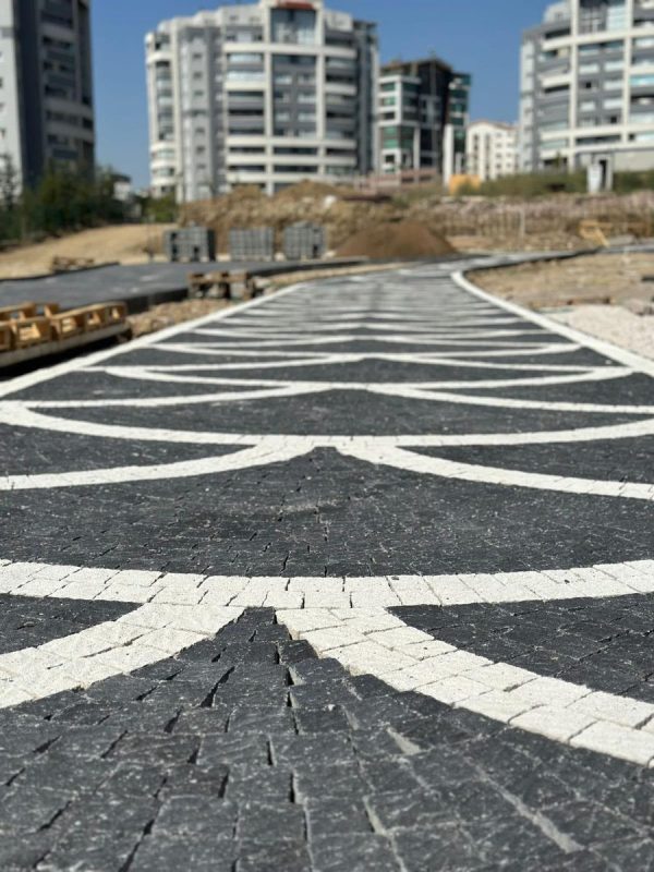 Konut sitesinde siyah beyaz yay desenli parke taşı yürüyüş yolu