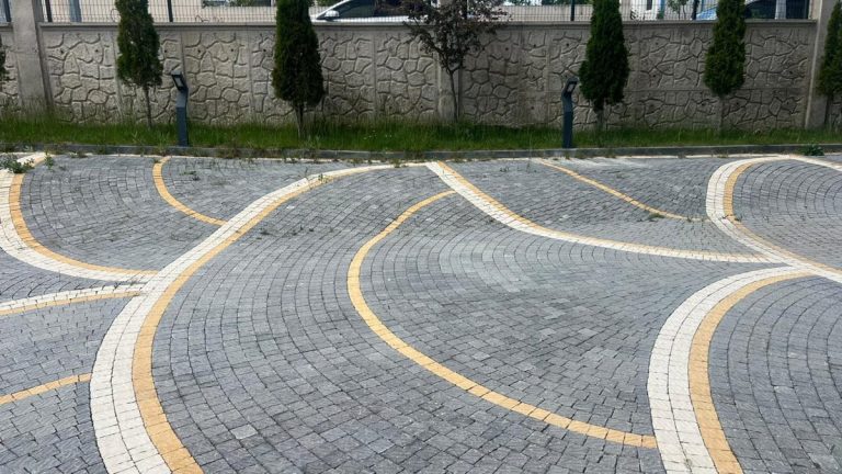 Site içi yolda yay desenli eski kilit taşı döşeme ve sarı bordür hatları